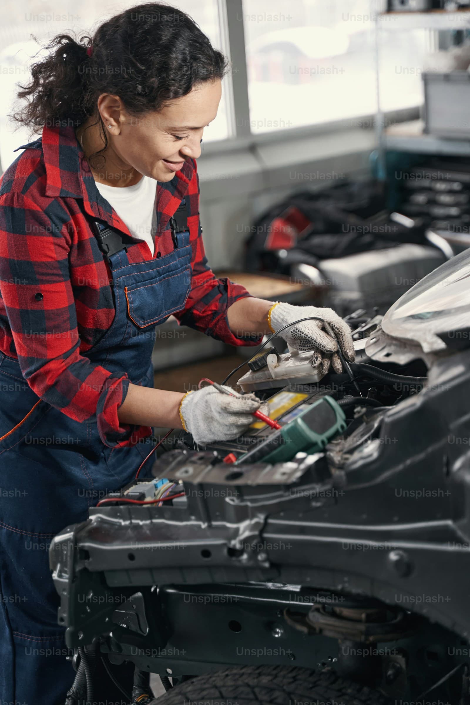 Technician testing electrical systems with a multimeter on a hybrid vehicle
